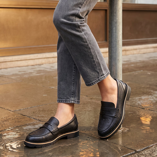 PENNY A person wearing waterproof black leather penny loafers and gray jeans stands on wet stone pavement next to a metal pole. - thumbnail image 2 of 93